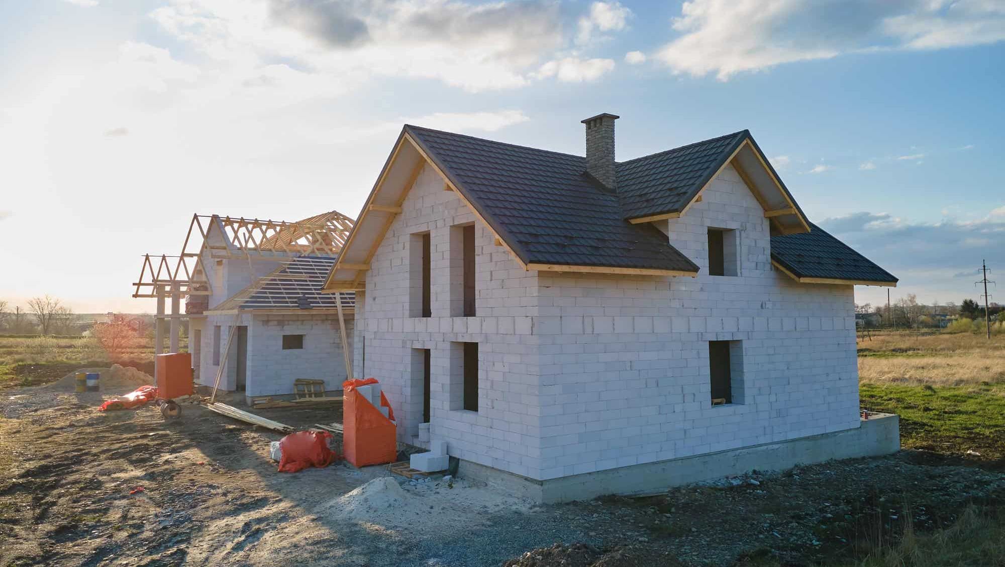 Nytt hus under bygging med tak montert og reisverk synlig i landlige omgivelser.